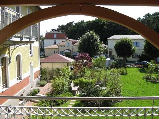 Von der Terrasse blickt man auf einen gepflegten Garten mit Bäumen und angrenzenden Häusern.