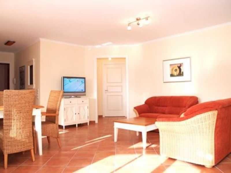 Wohn- und Essbereich mit rotem Sofa, Esstisch und Fernseher.