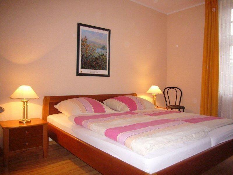 Schlafzimmer mit Doppelbett, zwei Nachttischen und einem Stuhl.