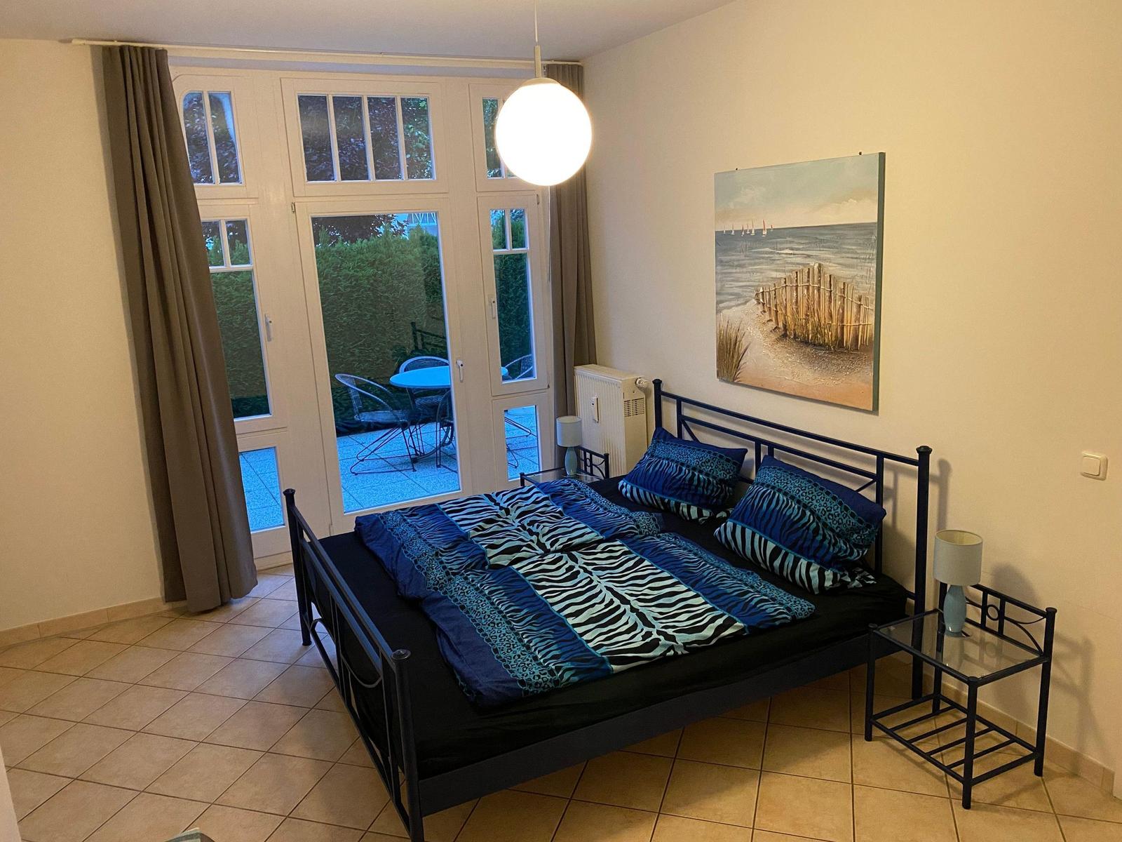 Schlafzimmer mit Bett, Fenster und Wandbild.
