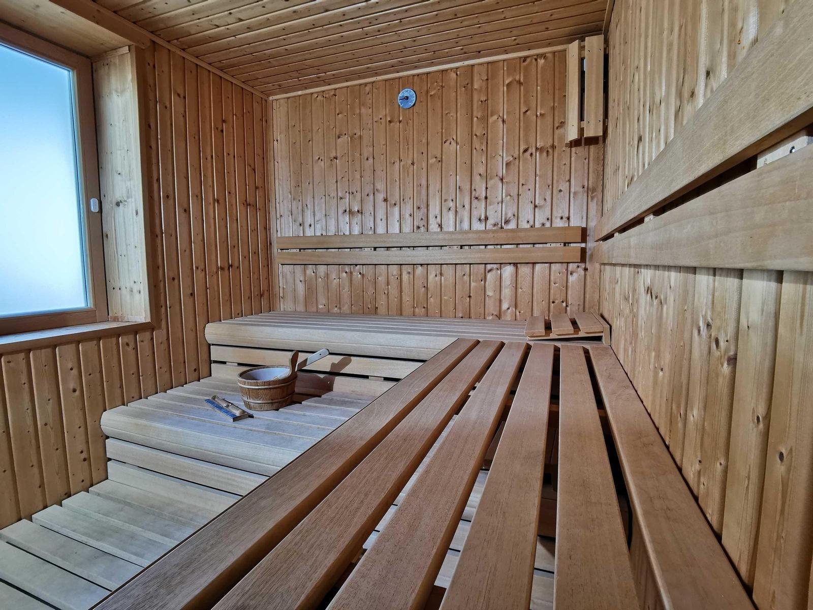 Sauna mit Holzbänken und Fenster. Thermometer an der Wand.