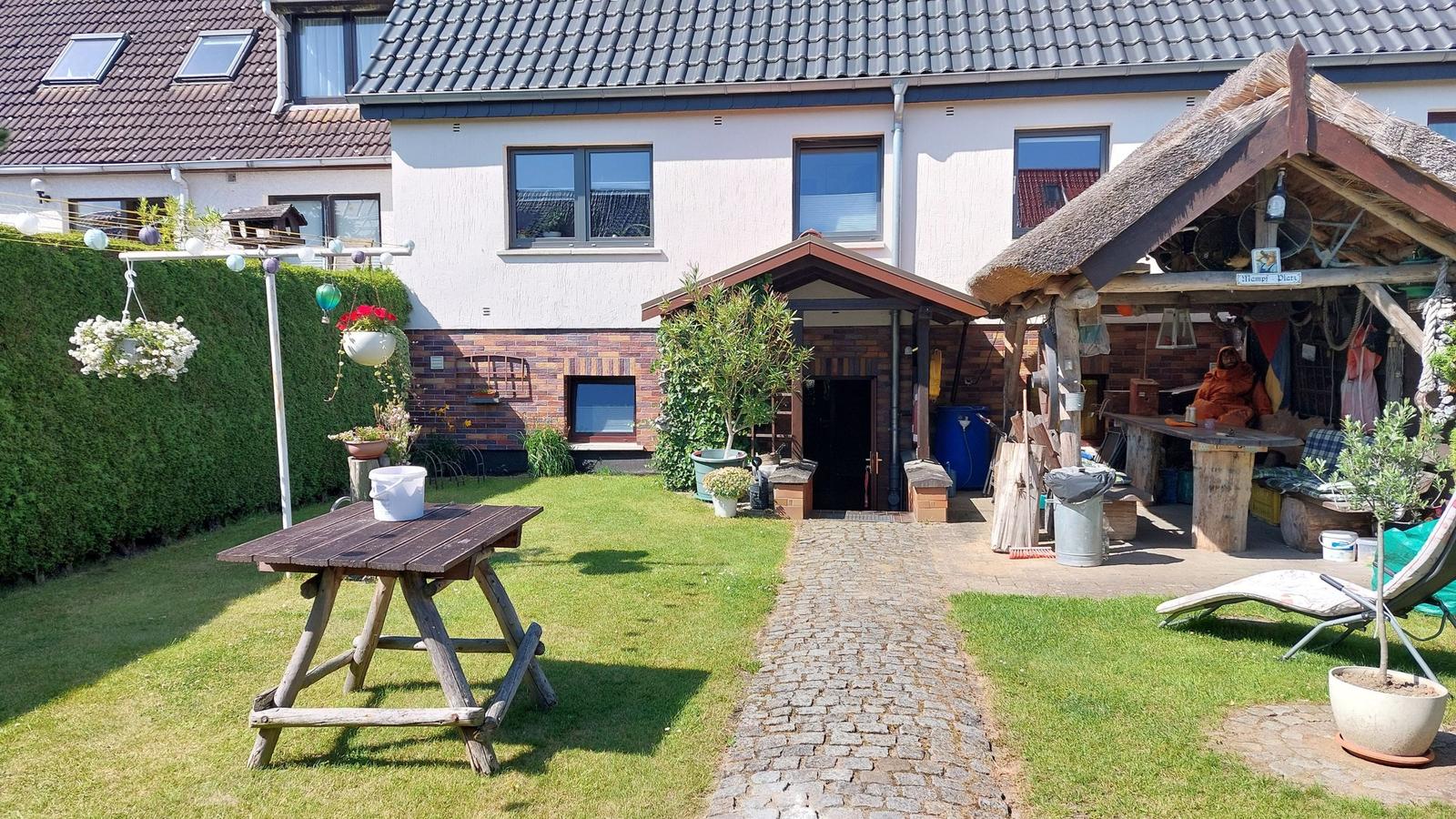 Hinterhof mit Picknicktisch, Steinweg und rustikalem Schuppen.