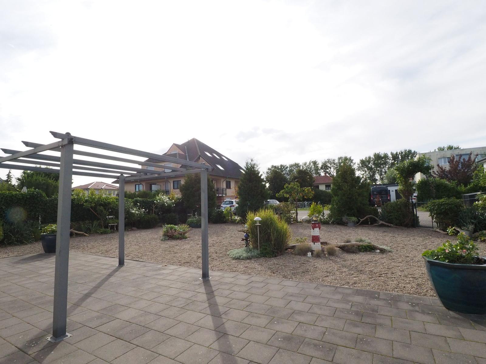 Terrasse mit Pavillon, Garten mit Steingarten und Wohnhaus im Hintergrund.