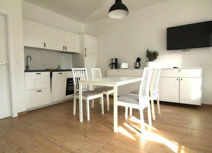 Küche und Essbereich mit weißer Einrichtung und Holzboden.