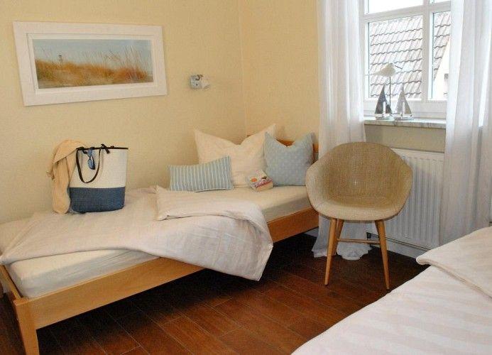 Zimmer mit zwei Betten, Sessel und Fenster mit Blick auf Dach