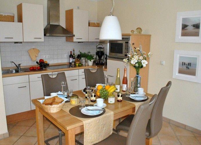 Küche und Essbereich mit Tisch, Stühlen, Küchenzeile und Blumen.
