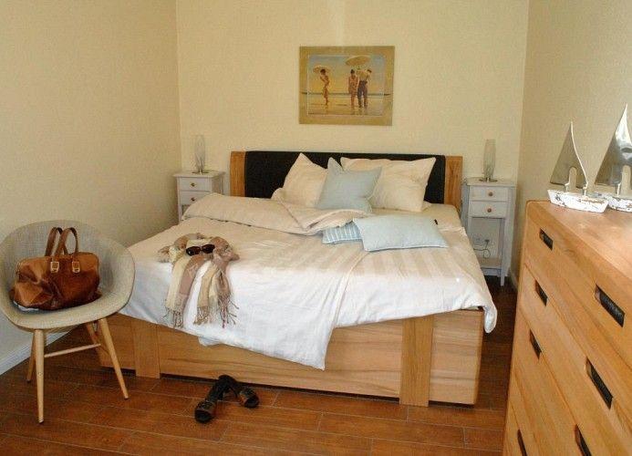 Schlafzimmer mit Bett, Nachttischen und Kleiderschrank. Wandbild und Sessel sind sichtbar.