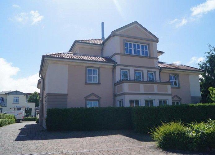 Ein zweistöckiges Haus mit Balkon und gepflegtem Garten. Hinterhof mit Zufahrt.