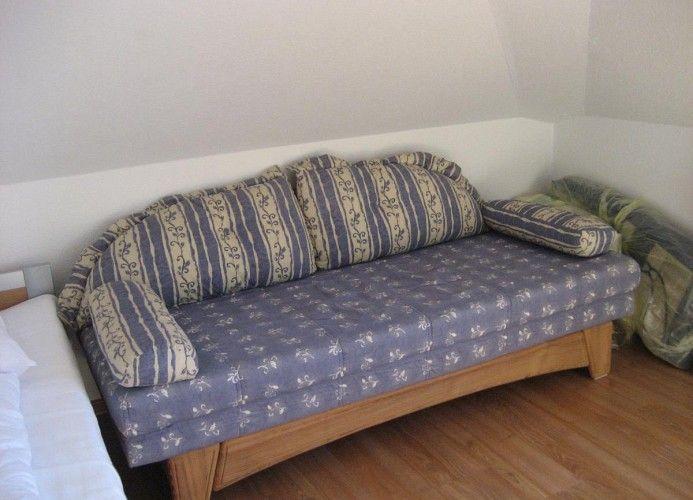Ein Sofa mit Streifenkissen und Blumenmuster auf Holzrahmen in einem Raum mit Holzboden.