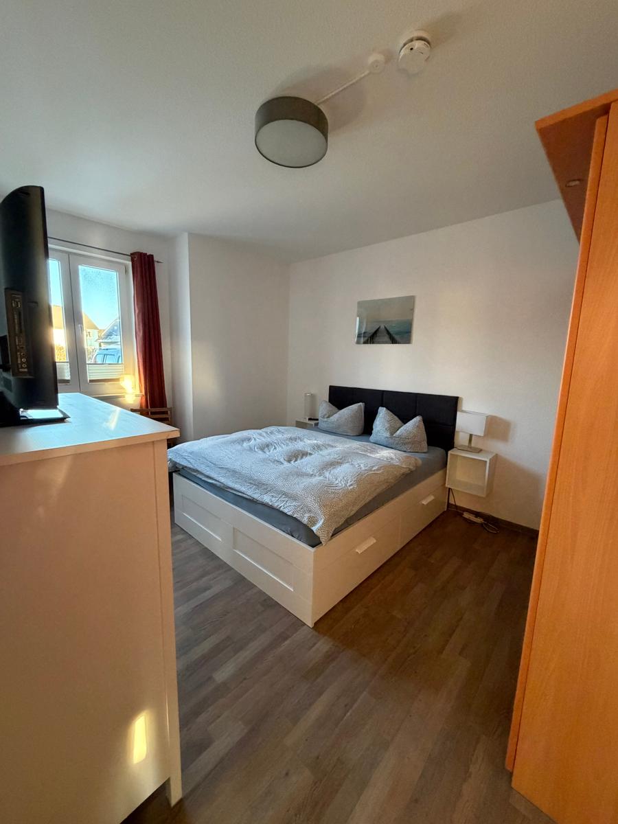 Schlafzimmer mit großem Schrank, Kommode und Fernseher.