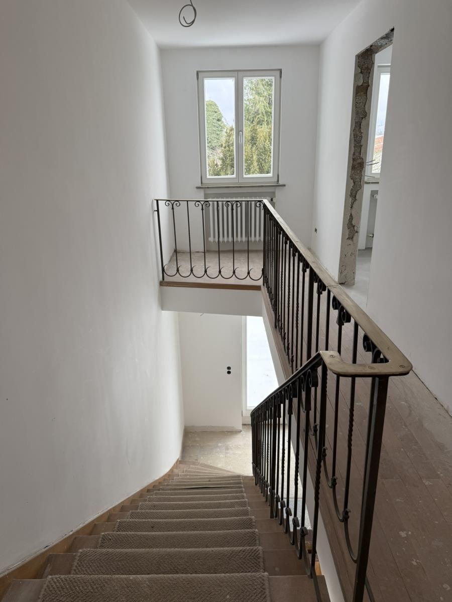 Staircase with wrought iron railing and window on upper floor