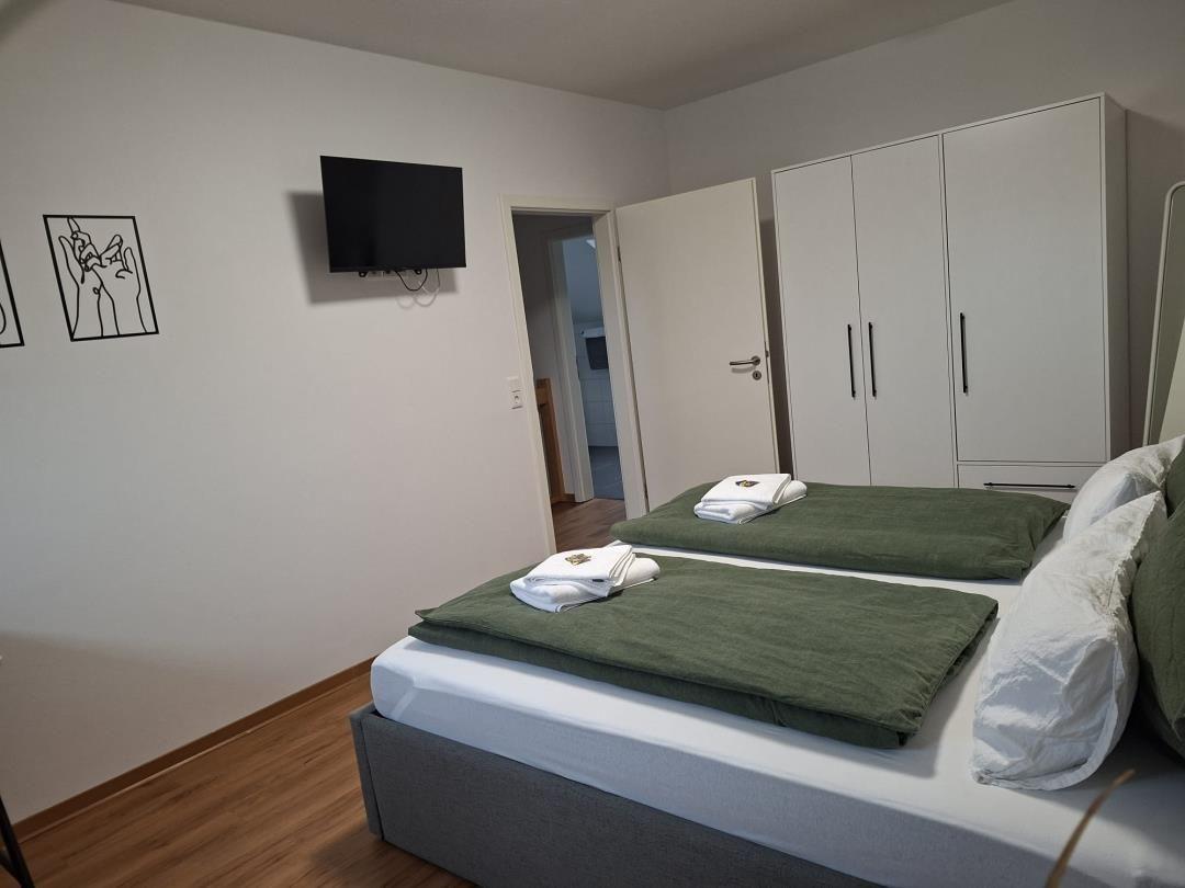 Schlafzimmer mit Doppelbett, Kleiderschrank und Wand-TV.