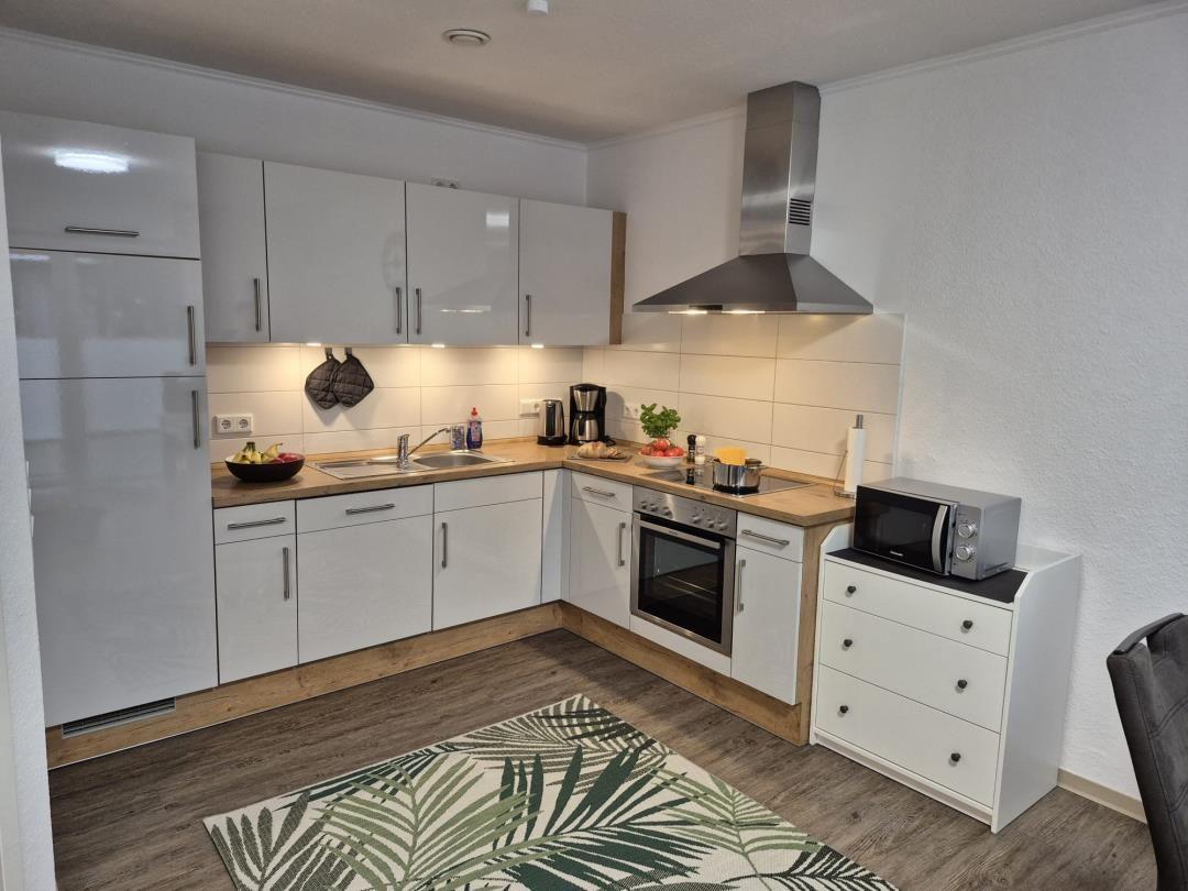 Moderne Küche mit weißen Schränken, Edelstahlherd und Mikrowelle.