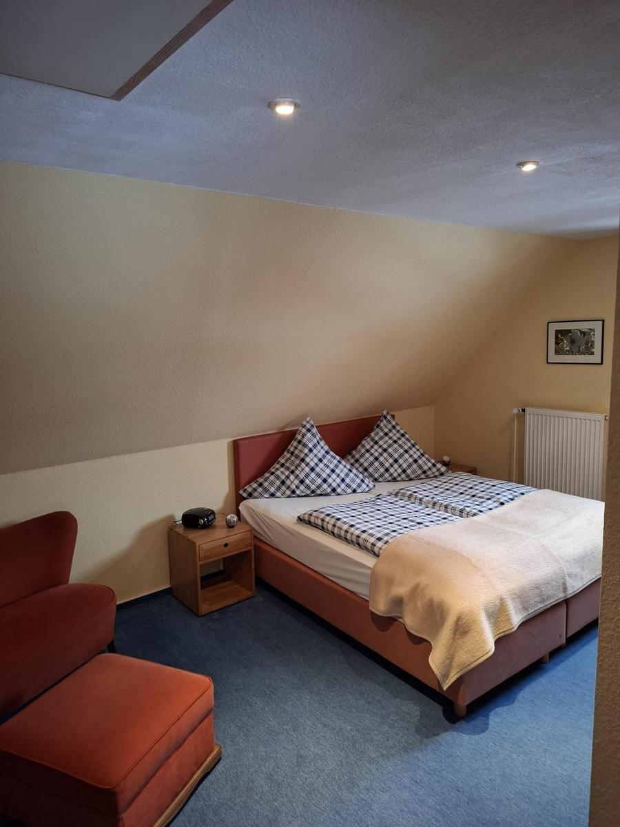 Schlafzimmer mit Doppelbett, rotem Sessel und Holznachttisch.