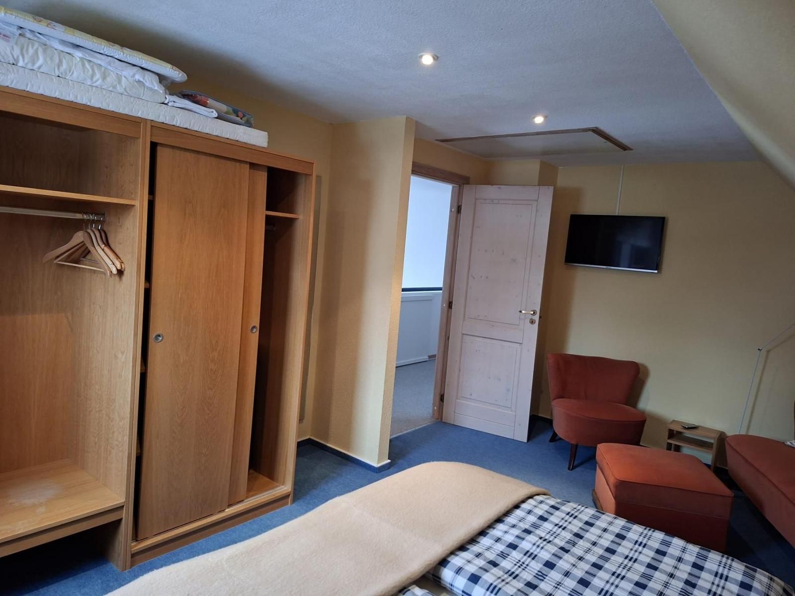 Zimmer mit Schlafbereich, Kleiderschrank und Sitzgelegenheit