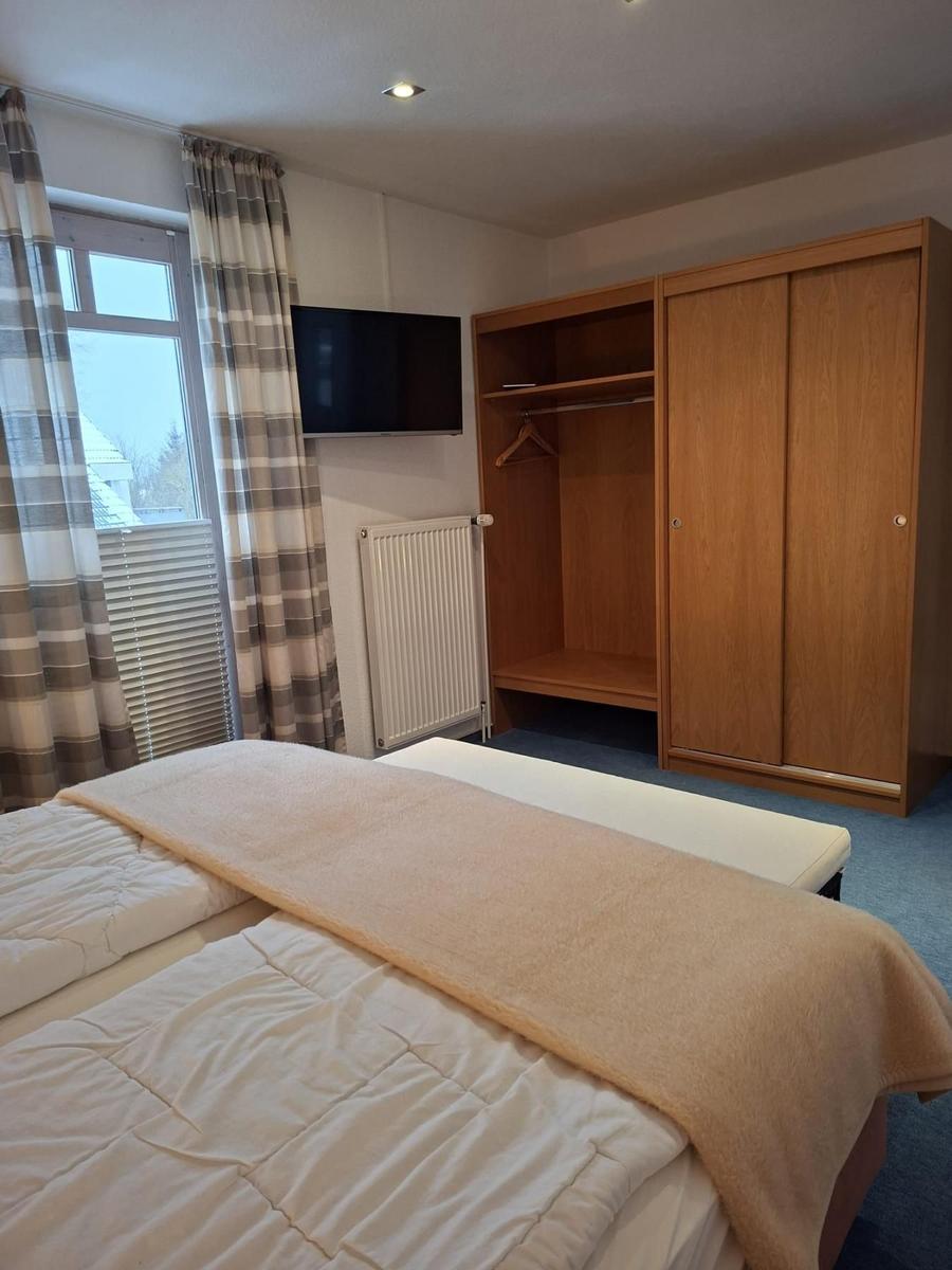 Schlafzimmer mit Doppelbett, Kleiderschrank und Fernseher.