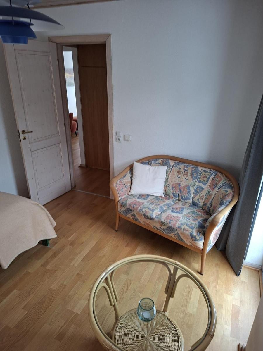 Wohnraum mit Sofa, Tisch und Tür zum Flur.