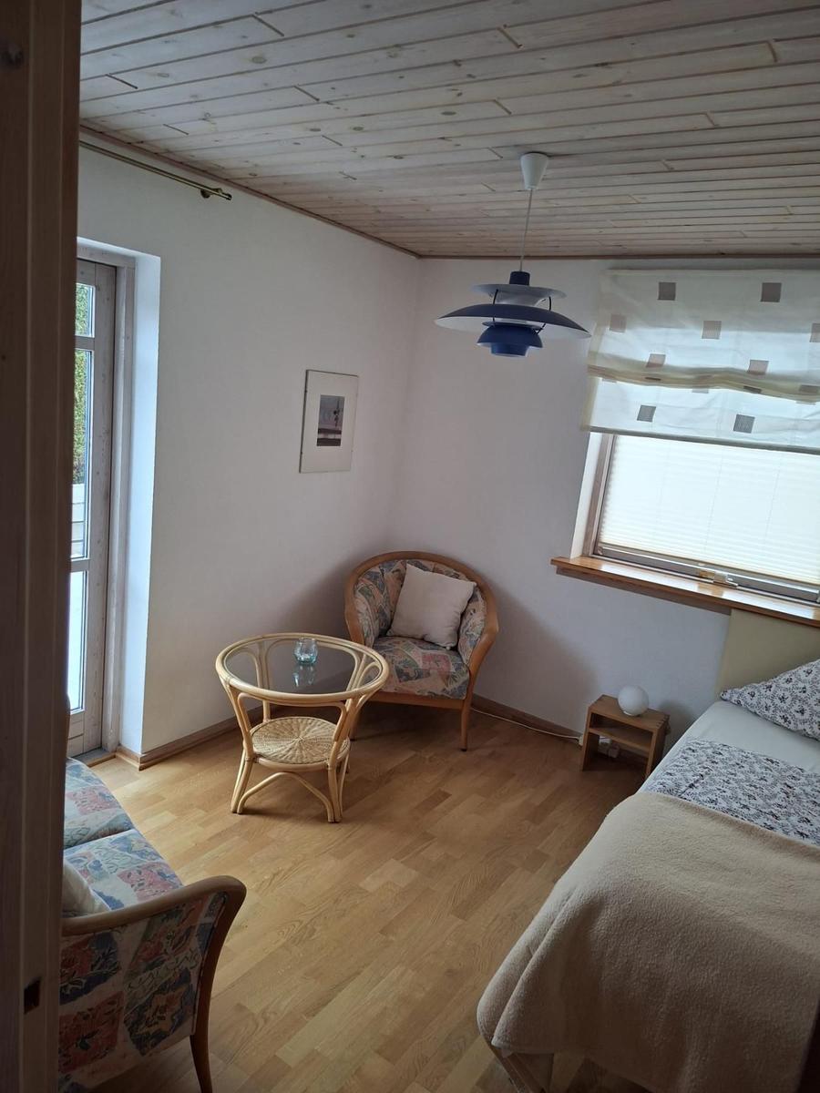 Ein Schlafzimmer mit Bett, Sessel, Tisch und Decke.