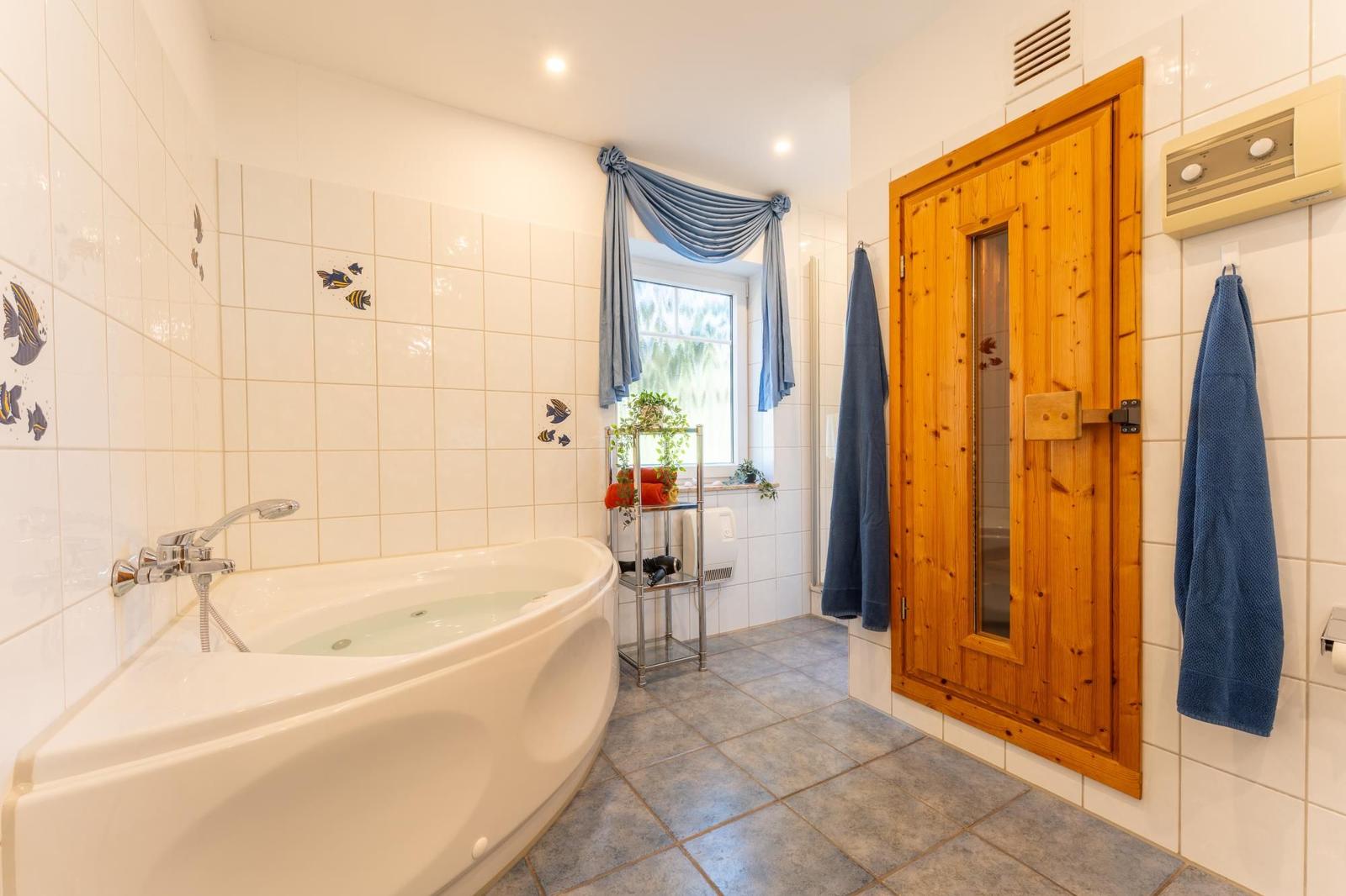 Badezimmer mit Whirlpool, Sauna und Fenster mit blauen Vorhängen.