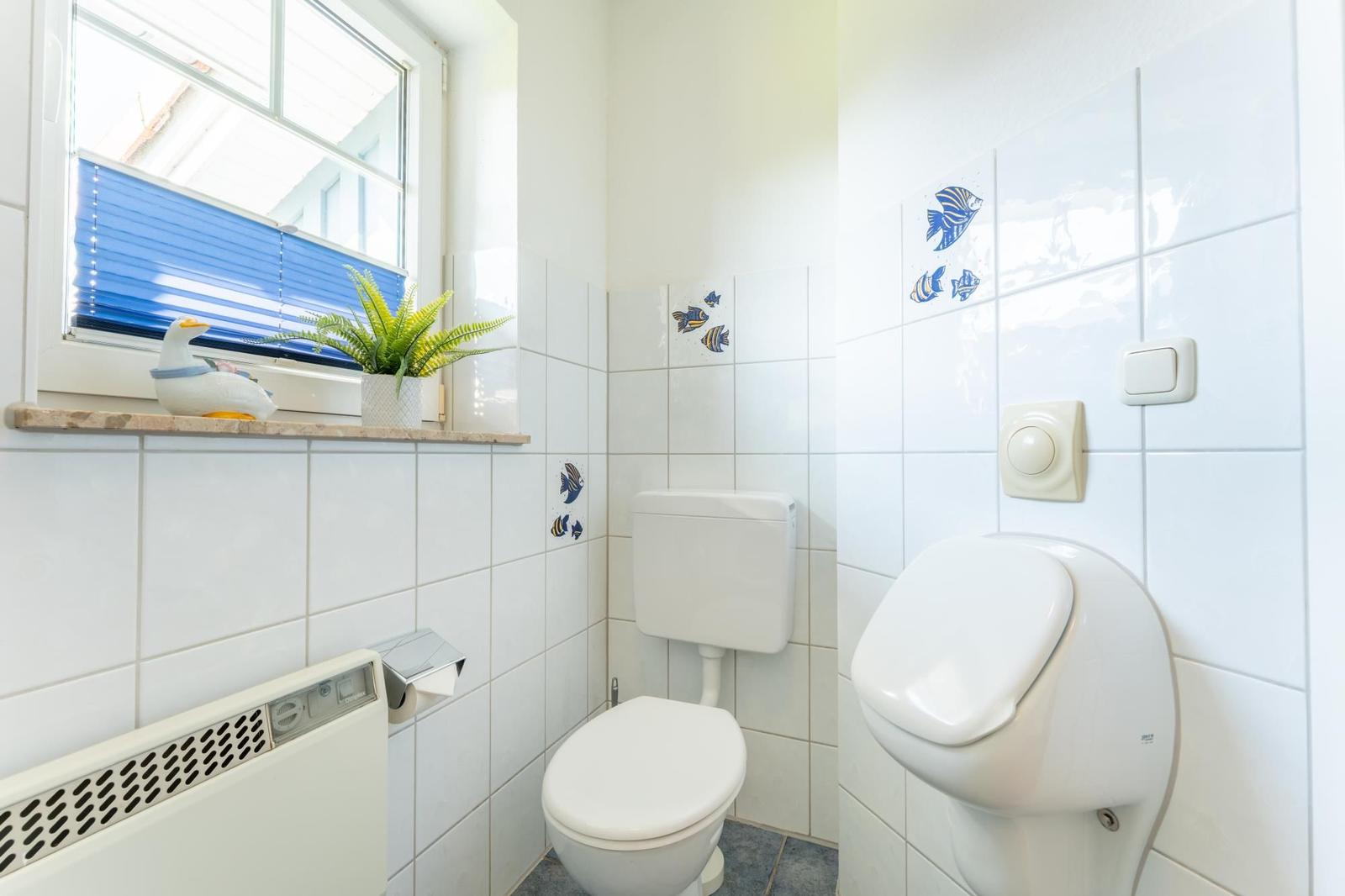 Badezimmer mit Toilette, WC und Fenster mit Pflanze und Ente.