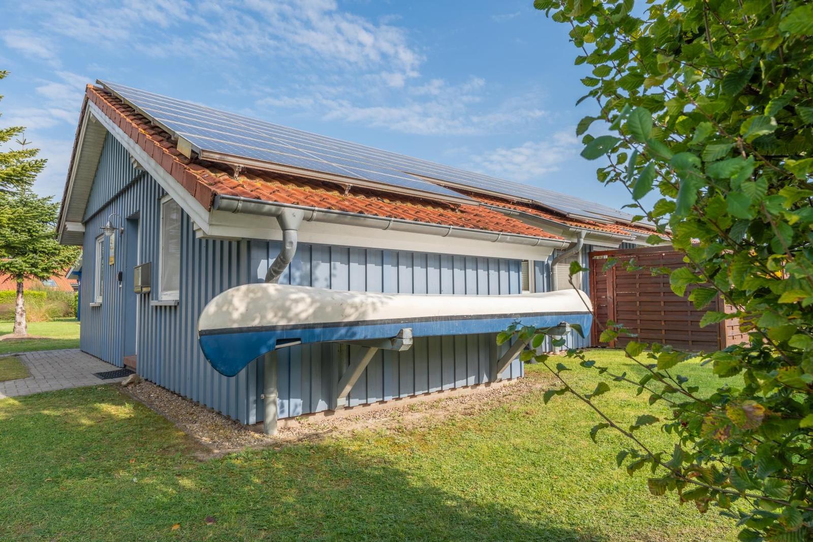 Blau gestrichenes Haus mit Solarpaneelen auf dem Dach und einem Boot an der Wand.