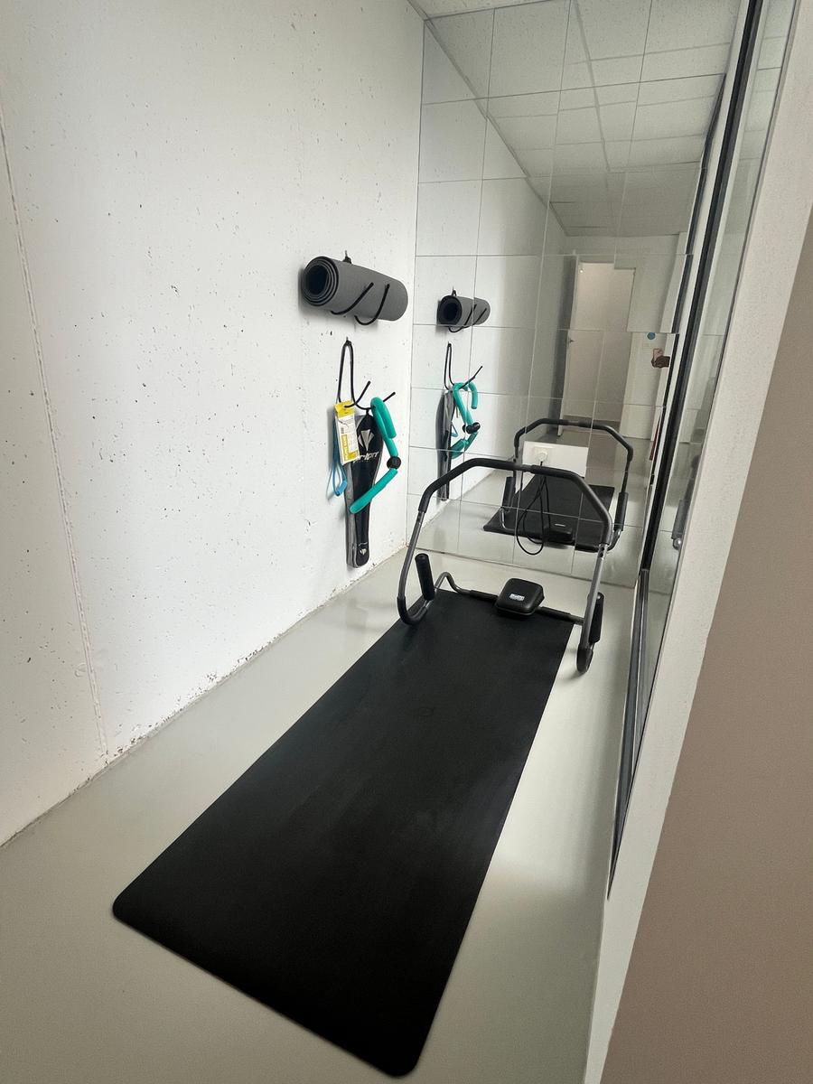 Fitness room with mat, exercise equipment, and wall mounts.