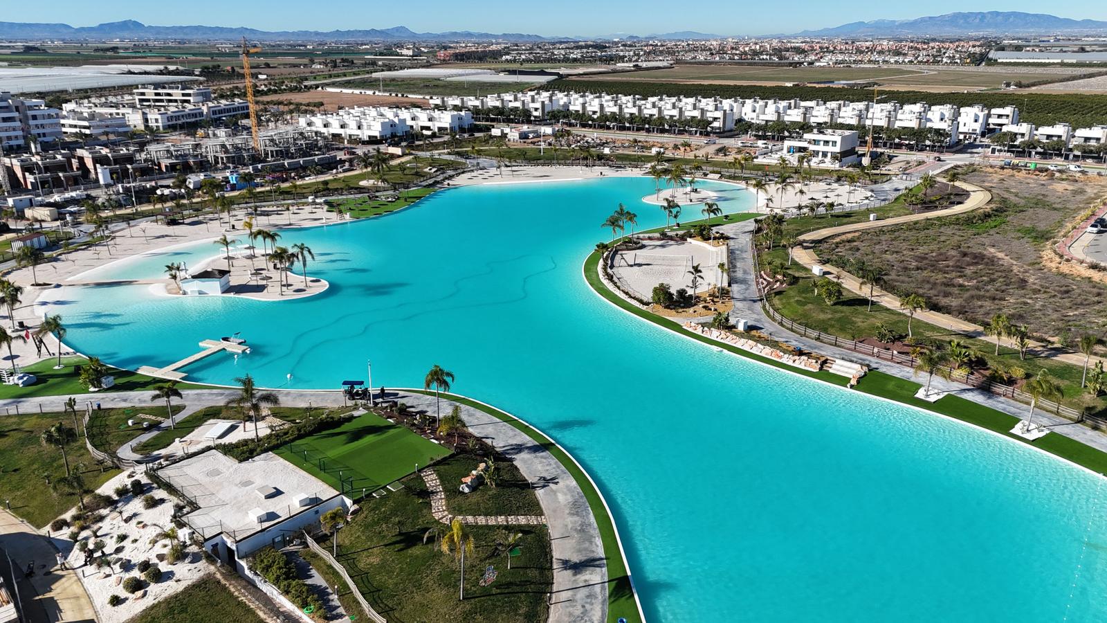 Large pool with beach area and surrounding green spaces
