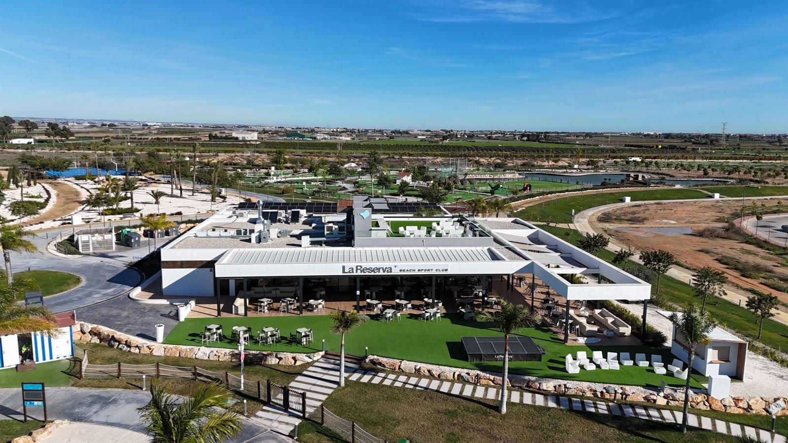 La Reserva Beach Sport Club with terrace, tables, and palm trees.