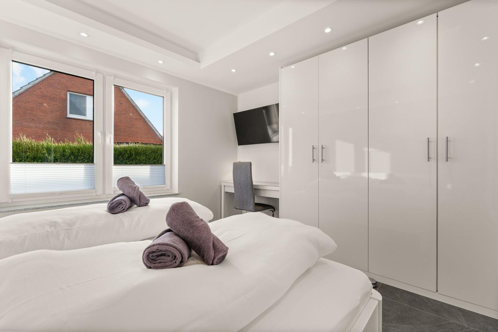 Zimmer mit Doppelbett, Schrank und Fenster mit Blick auf Garten.