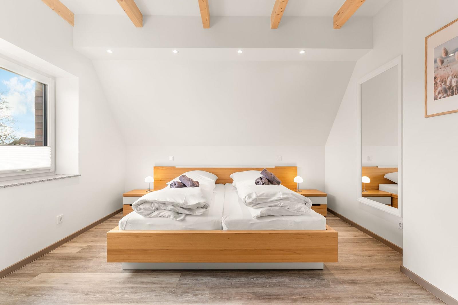 Schlafzimmer mit Holzbett, Fenster und Spiegeltür