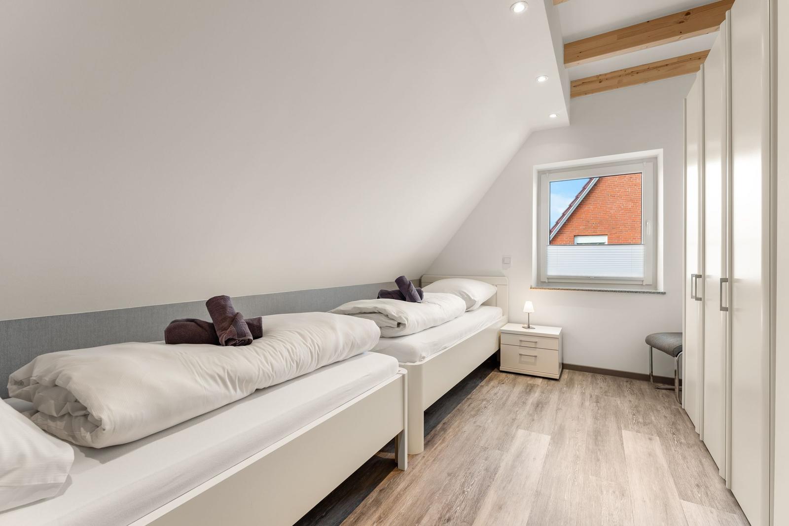 Zimmer mit zwei Betten, Schrank und Fenster mit Blick auf Dach