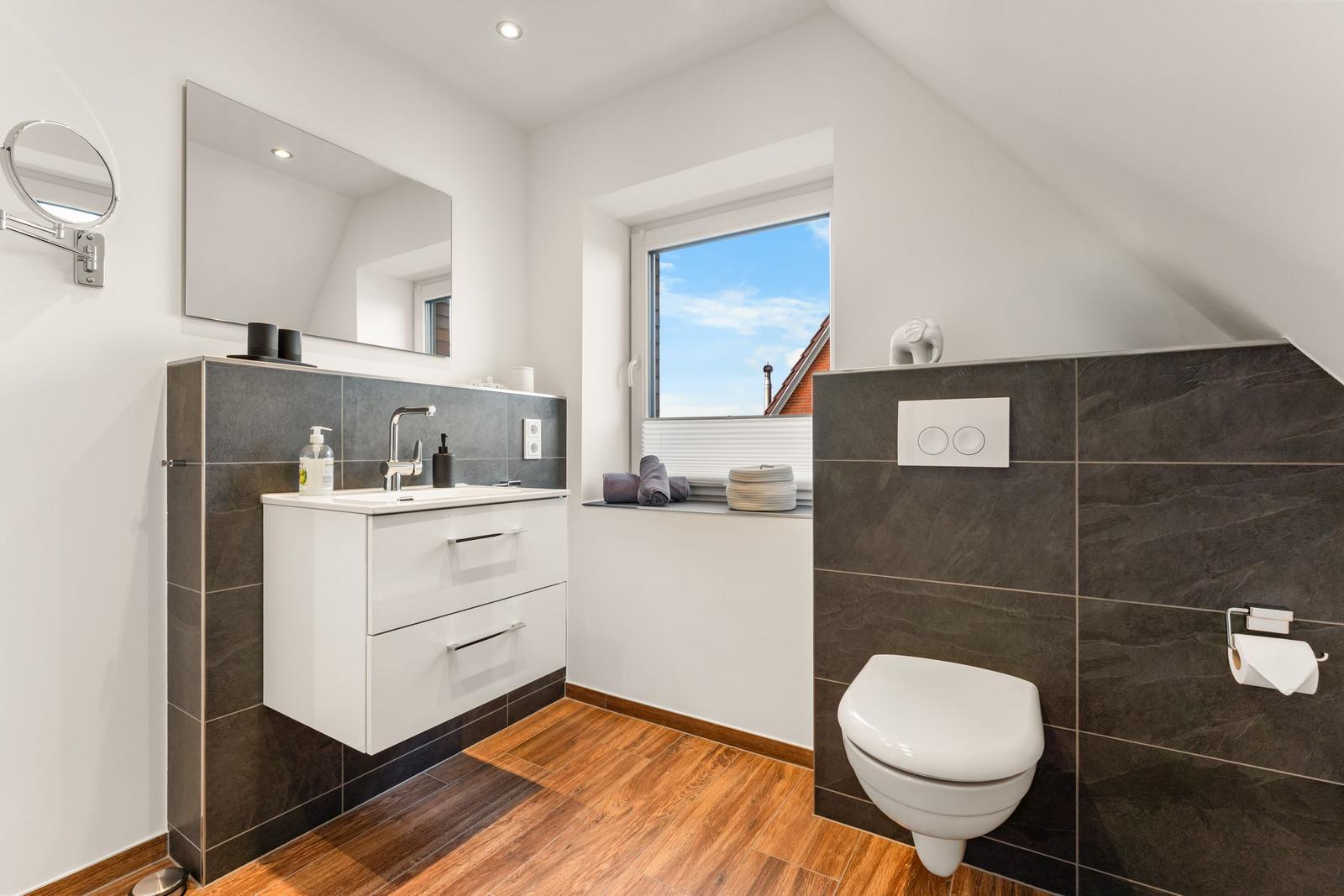Badezimmer mit Waschbecken, Toilette und Fenster mit Blick.