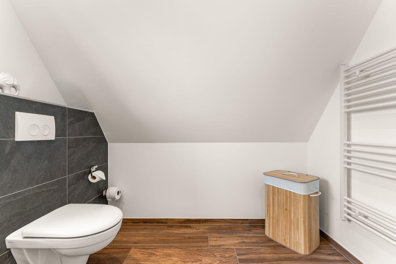 Badezimmer mit Toilette, Heizung und Bambus-Korb.