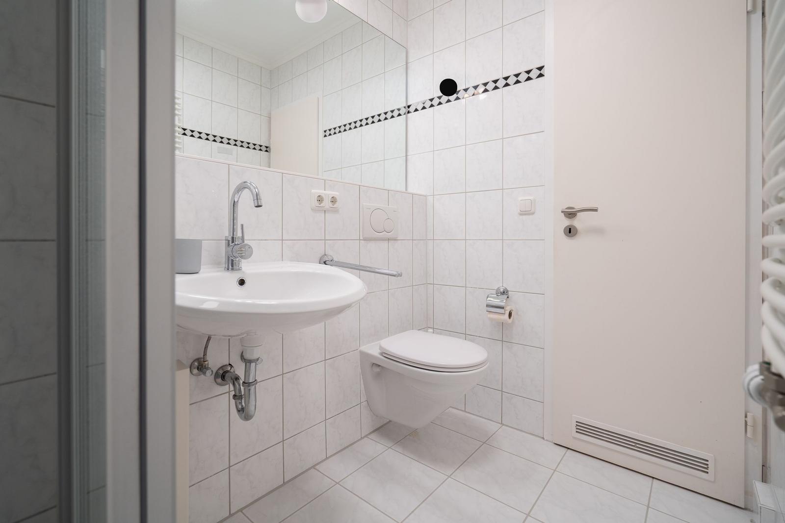 Badezimmer mit Waschbecken, Toilette und Spiegel an der Wand.