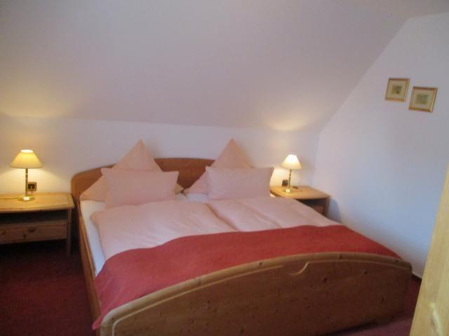 Schlafzimmer mit Doppelbett, zwei Nachttischen und Lampen an der schrägen Wand.