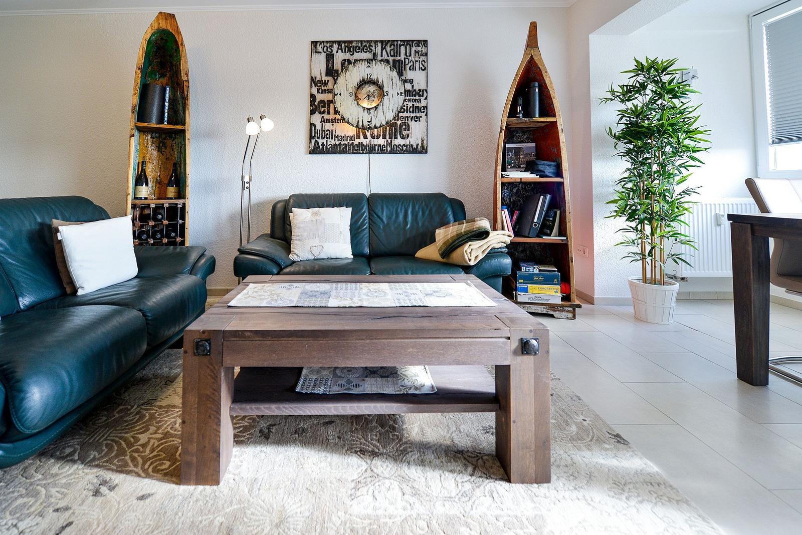 Ein Wohnzimmer mit zwei Ledersofas, einem Holztisch und Bootsbüchern an den Wänden.