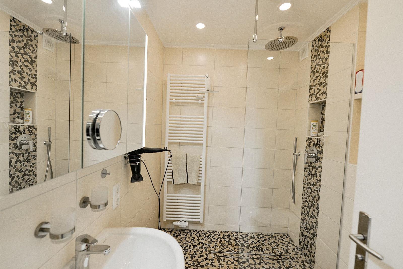 Badezimmer mit Dusche, Spiegel und Heizkörper