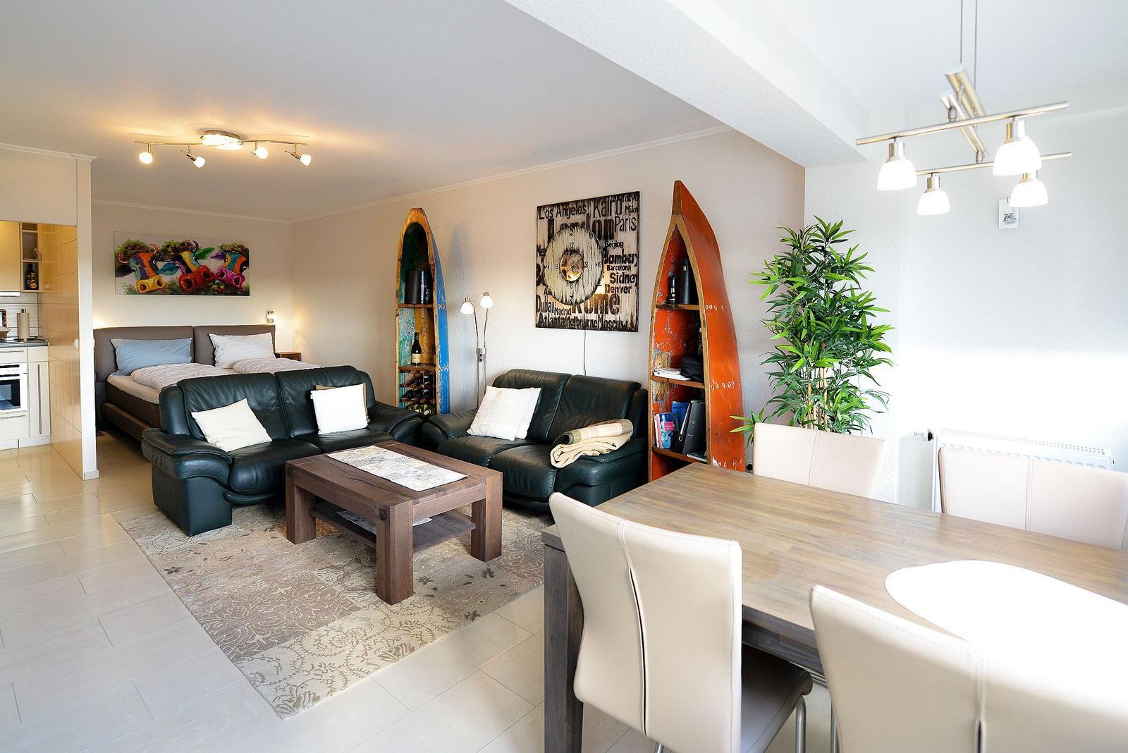 Wohn- und Essbereich mit Sofa, Tisch und Küchenbereich im Hintergrund.