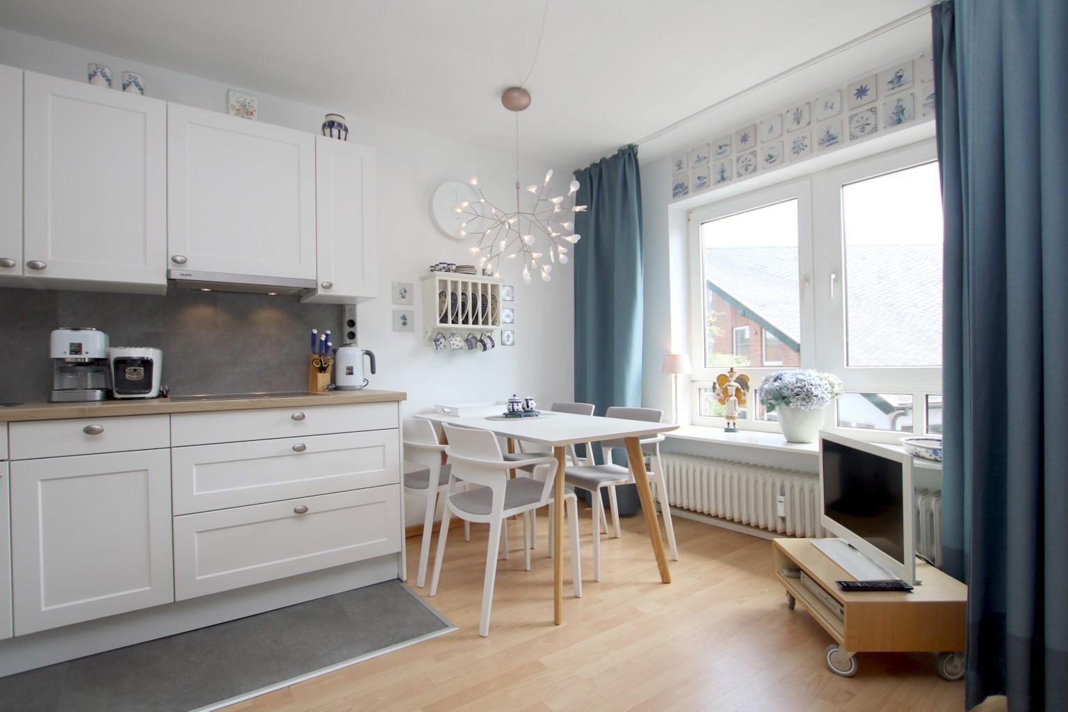 Küche mit Esstisch, TV und Fenster mit Blick nach draußen.