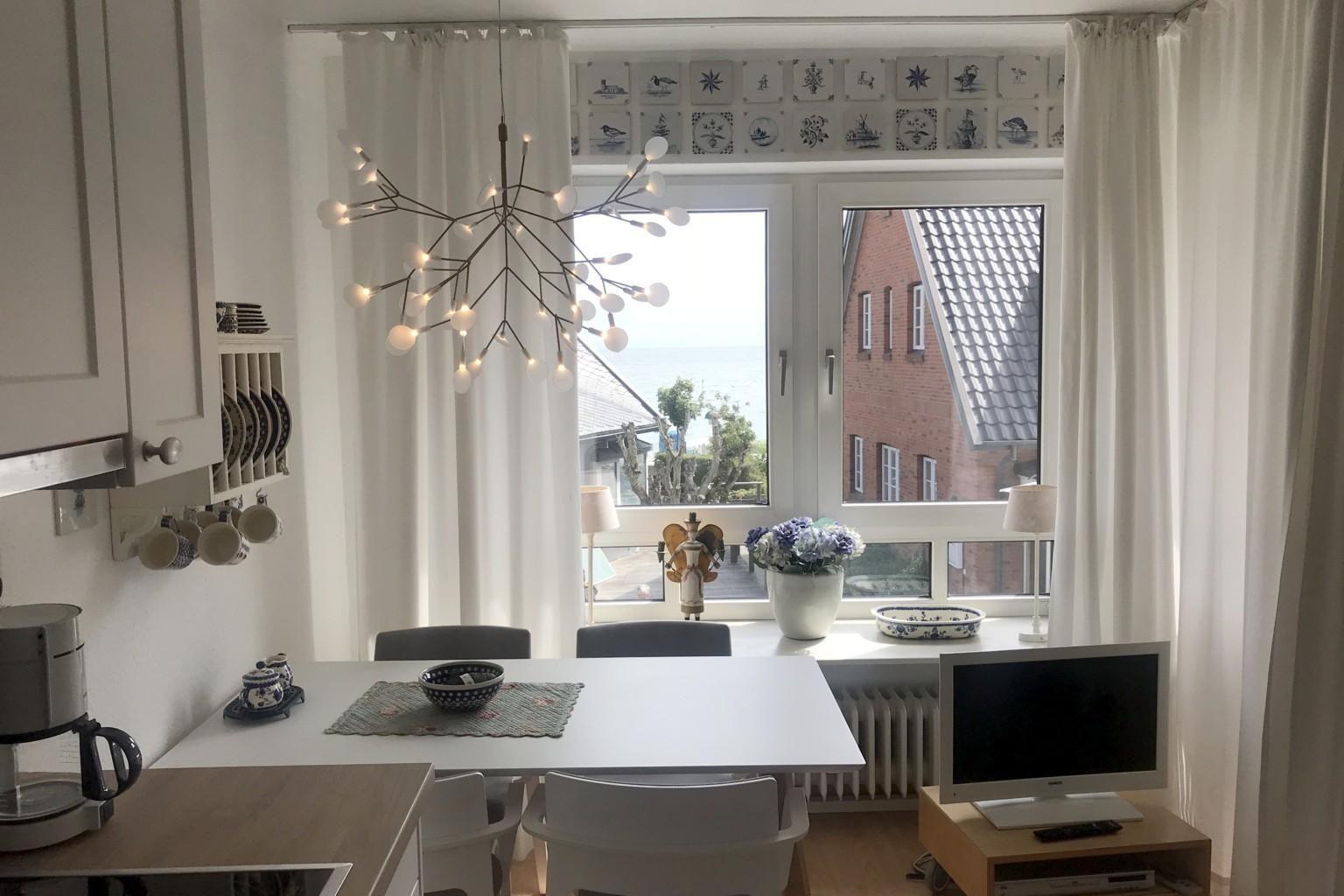 Essbereich mit Tisch, Stühlen und Fensterblick auf Meer und Dach