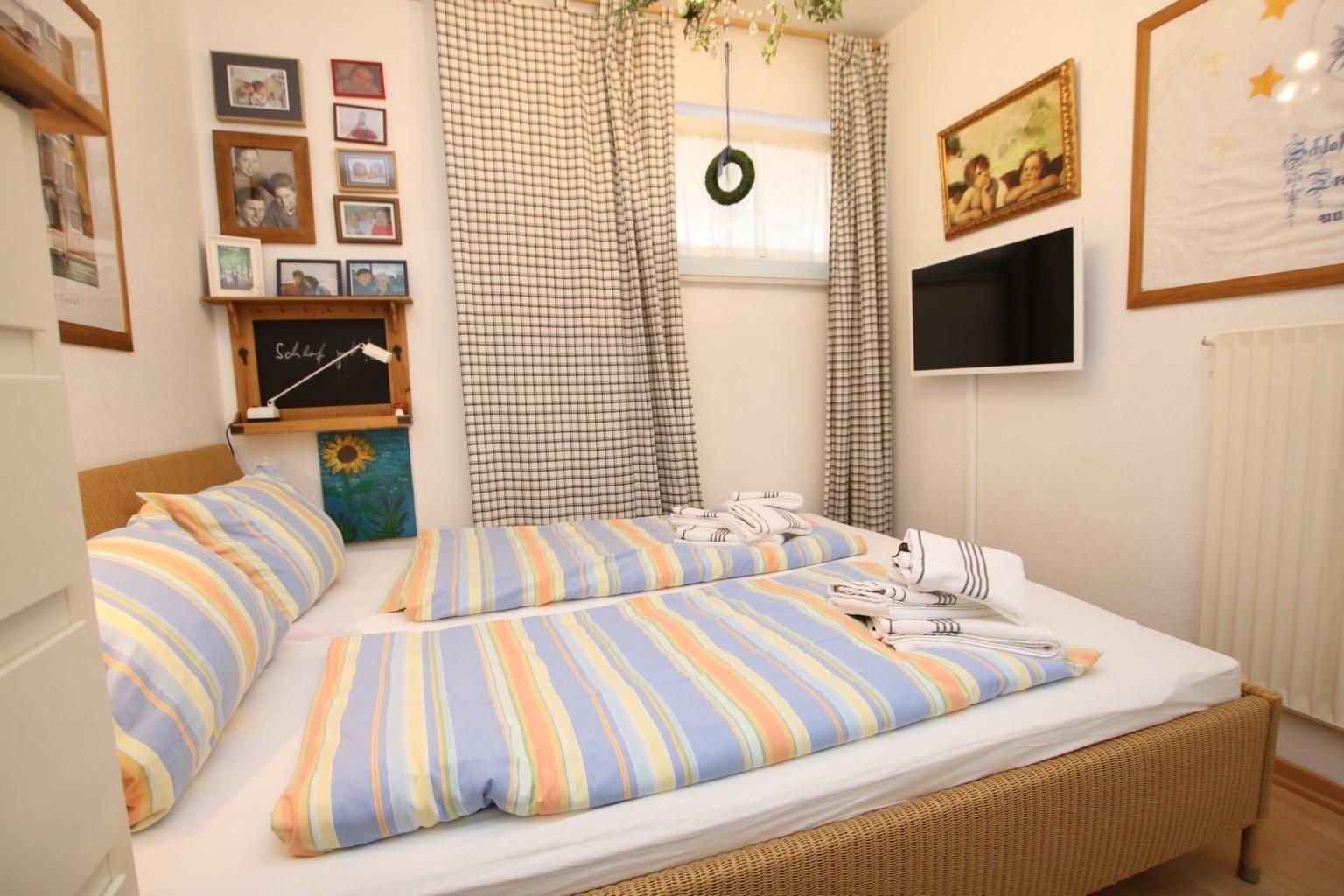 Ein Schlafzimmer mit einem Bett, Vorhängen, Wandbildern und einer Wandhalterung für einen Fernseher.