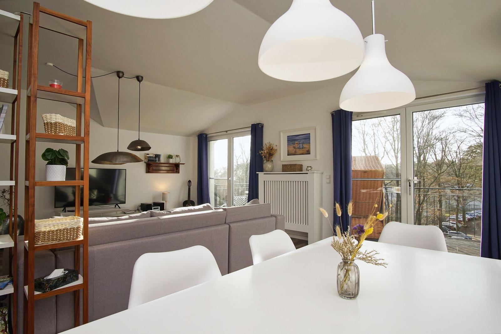 Wohn- und Essbereich mit Sofa, Esstisch und Balkonansicht.