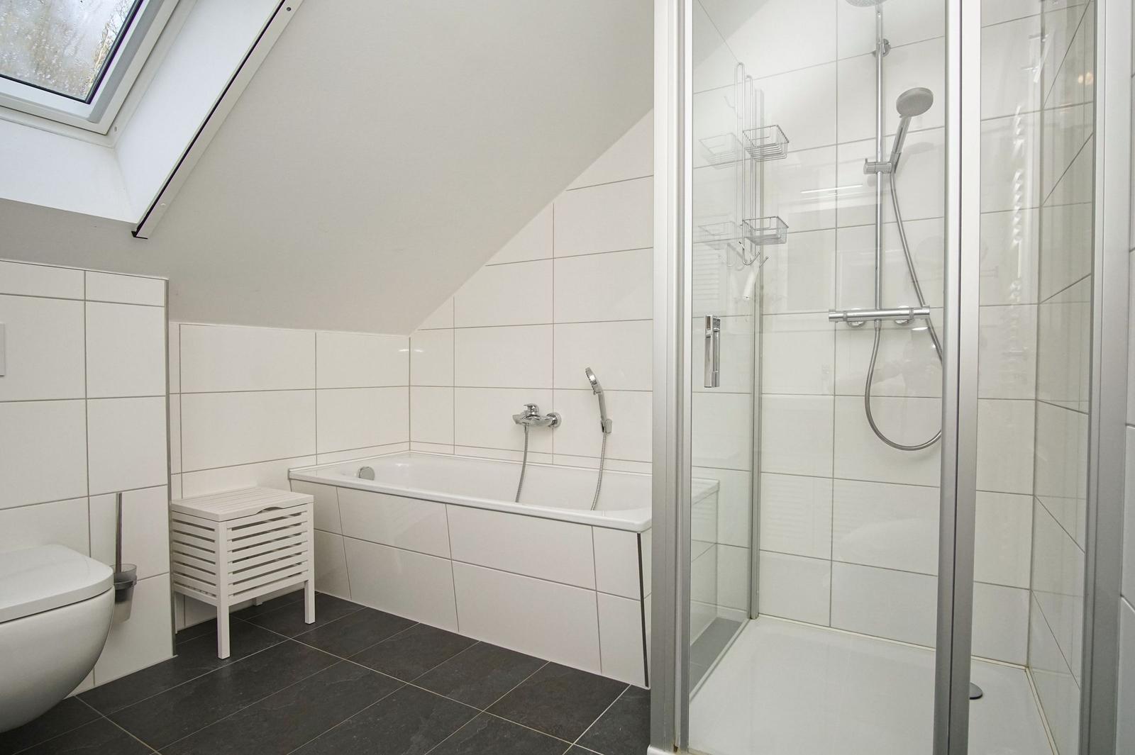 Badezimmer mit Dusche, Badewanne und Dachfenster