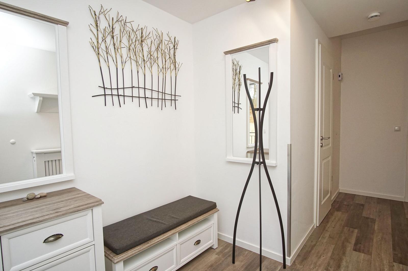 Eingangsbereich mit Spiegeln, Sitzbank und Wanddekoration.