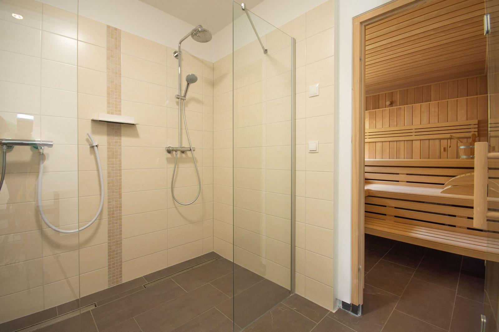 Dusche mit Glaswand und Sauna mit Holzbänken