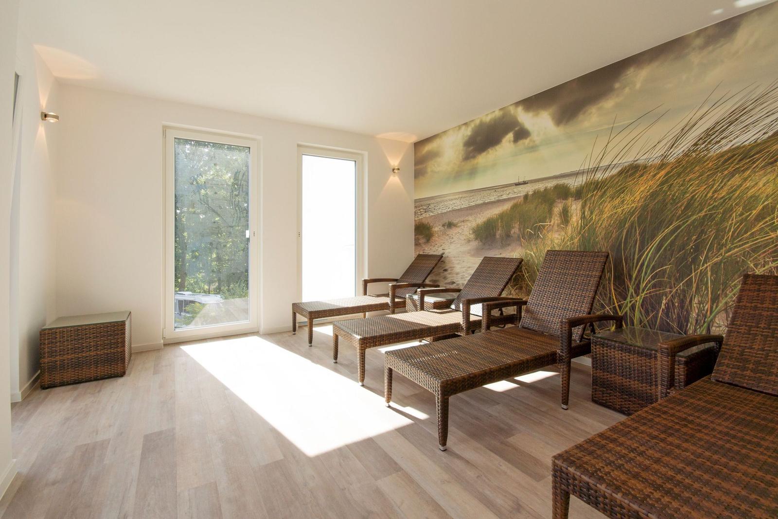 Raum mit Wicker-Liegen, Wandbild und Türen zum Garten.