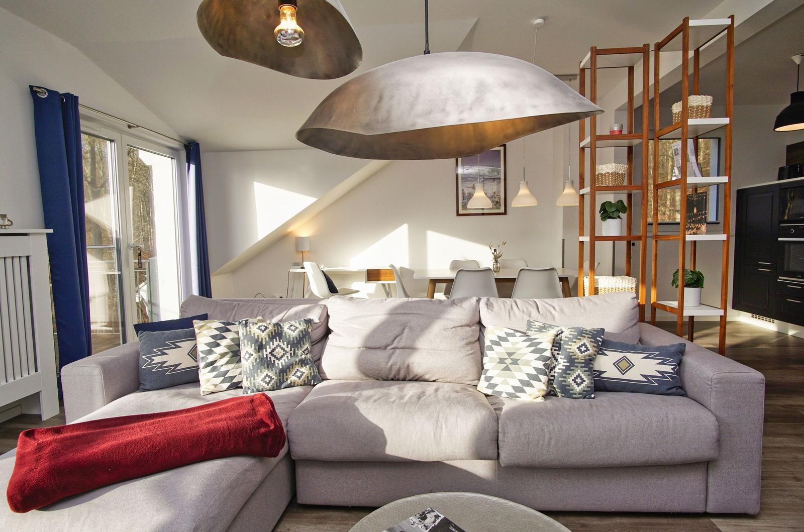 Großer Wohnbereich mit Sofa, Deckenleuchten und Blick auf Terrasse.