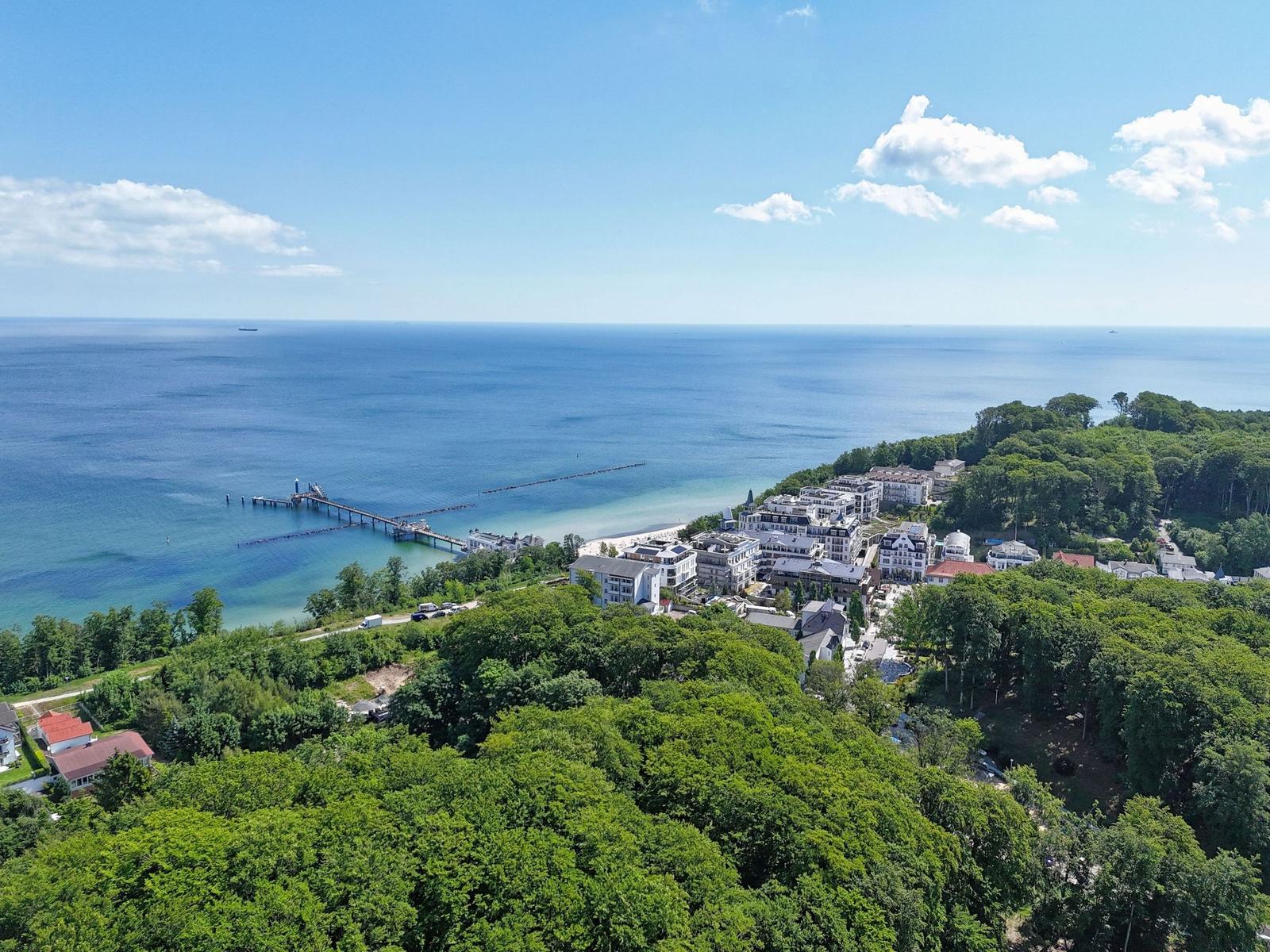 Panoramablick auf Strand, Hafen und grüne Landschaft mit Hotels und Häusern.