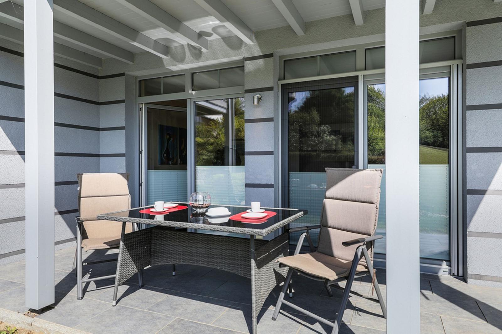 Terrasse mit Tisch und zwei Stühlen unter Dach