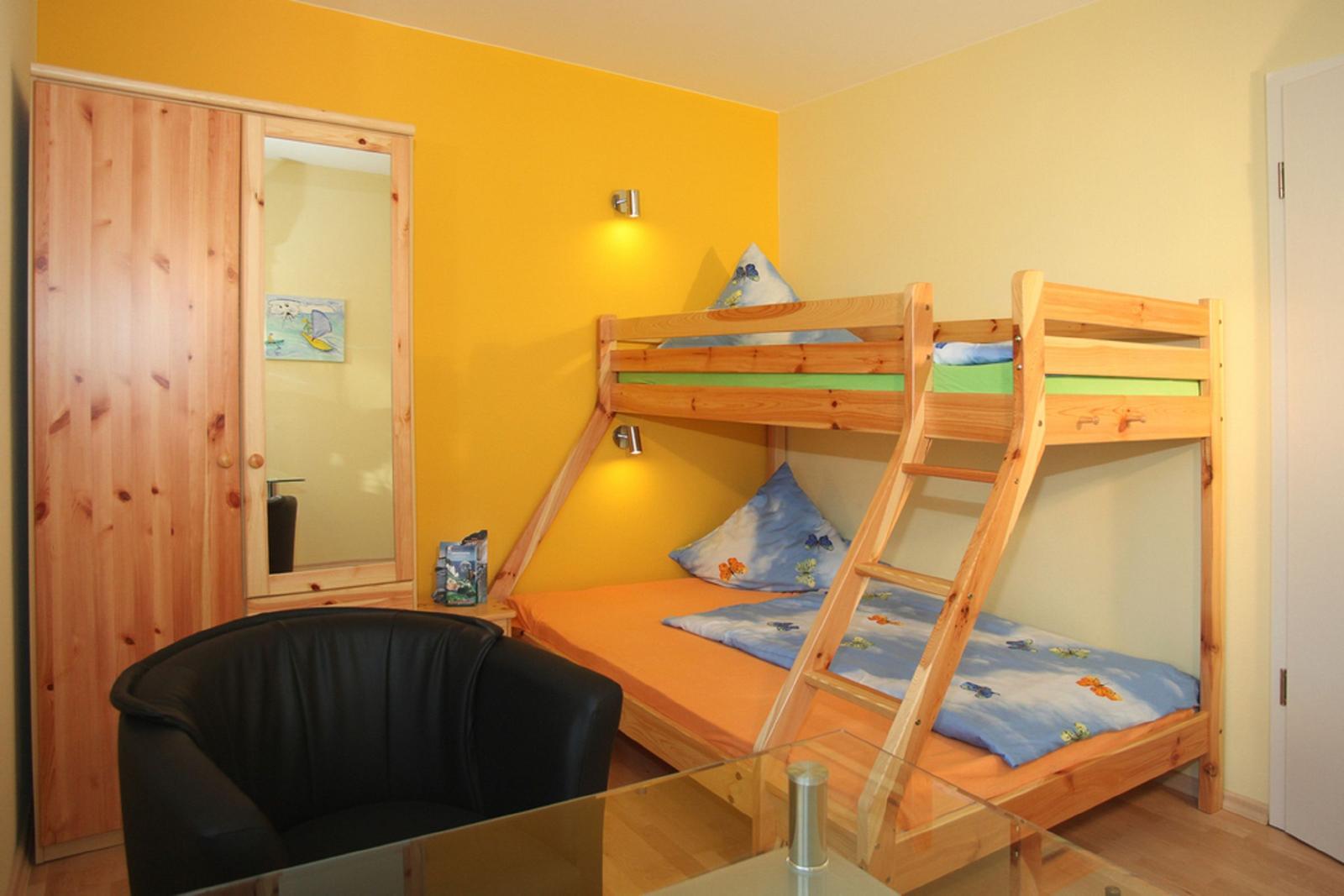 Ein Schlafzimmer mit einem Holzbett, einem Kleiderschrank und einem schwarzen Sessel.